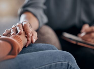 Therapist holding client’s hand while discussing burnout and identity loss