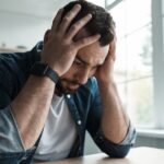 A person places hi hands on his head as he considers anxiety therapy in Milwaukee
