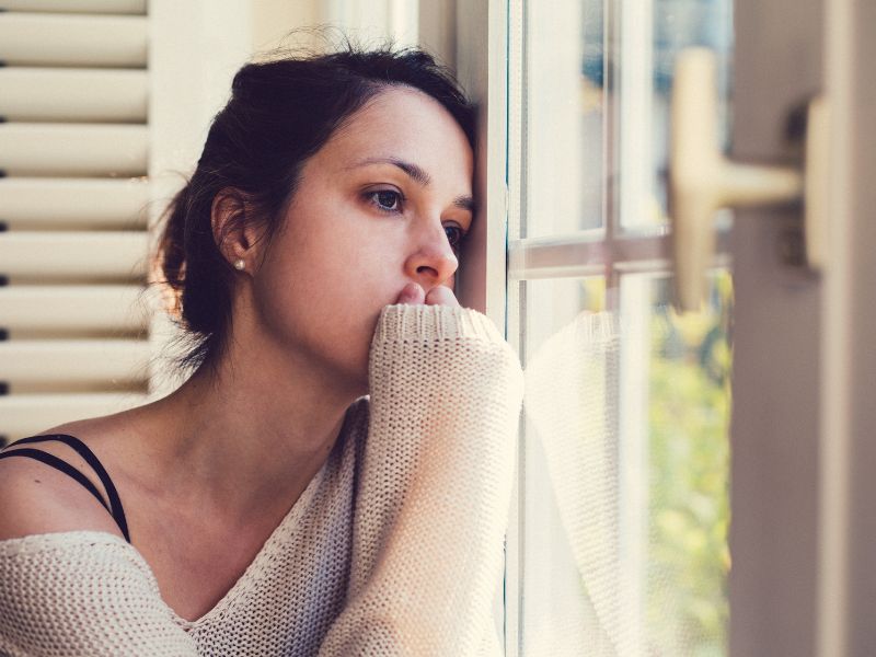 A woman stares out the window, considering depression counseling in Milwaukee.
