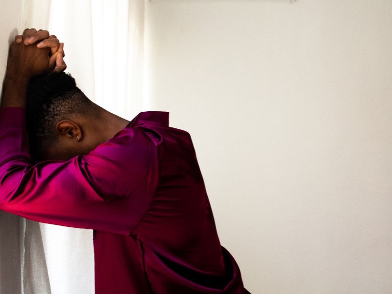 A person places their head against the wall, considering trauma therapy in Milwaukee