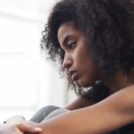 A woman looks out the window in contemplation, considering trauma-informed therapy.