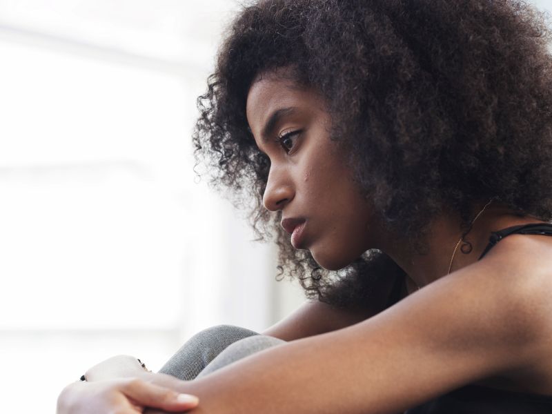 A woman looks out the window in contemplation, considering trauma-informed therapy.